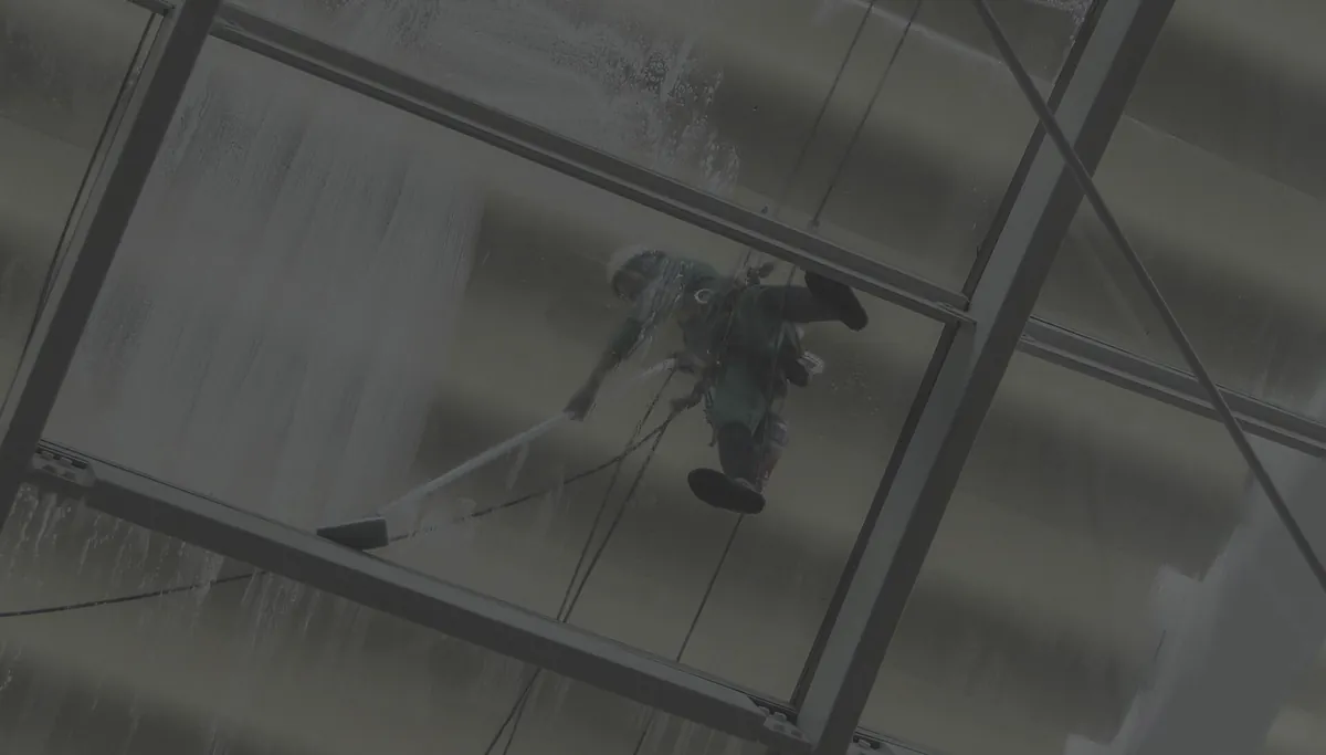 Technician cleaning the glass exterior of a commercial building