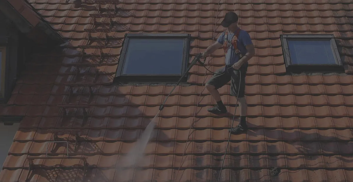 A technician soft-washing algae and stains from a tile roof